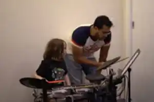Young boy drumming at Besharp Music School, Adelaide, showcasing his rhythmic talent and enthusiasm for percussion.