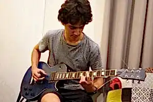 Teenager strumming a guitar at Besharp Music School, Adelaide, demonstrating skill and artistic dedication.