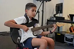 Boy demonstrating his guitar skills during a music lesson, mentored by his teacher at Besharp Music School, Adelaide.